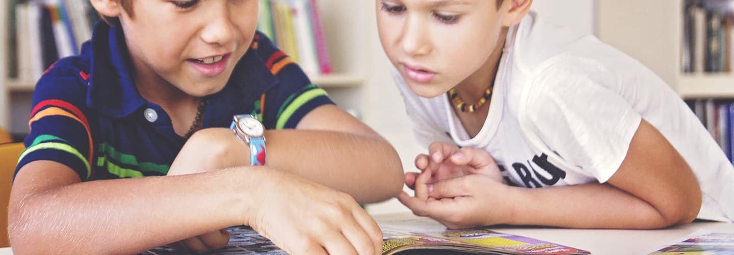 Two children looking over a book together