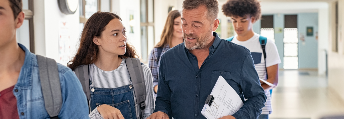 A teacher talking to a student in the hallway