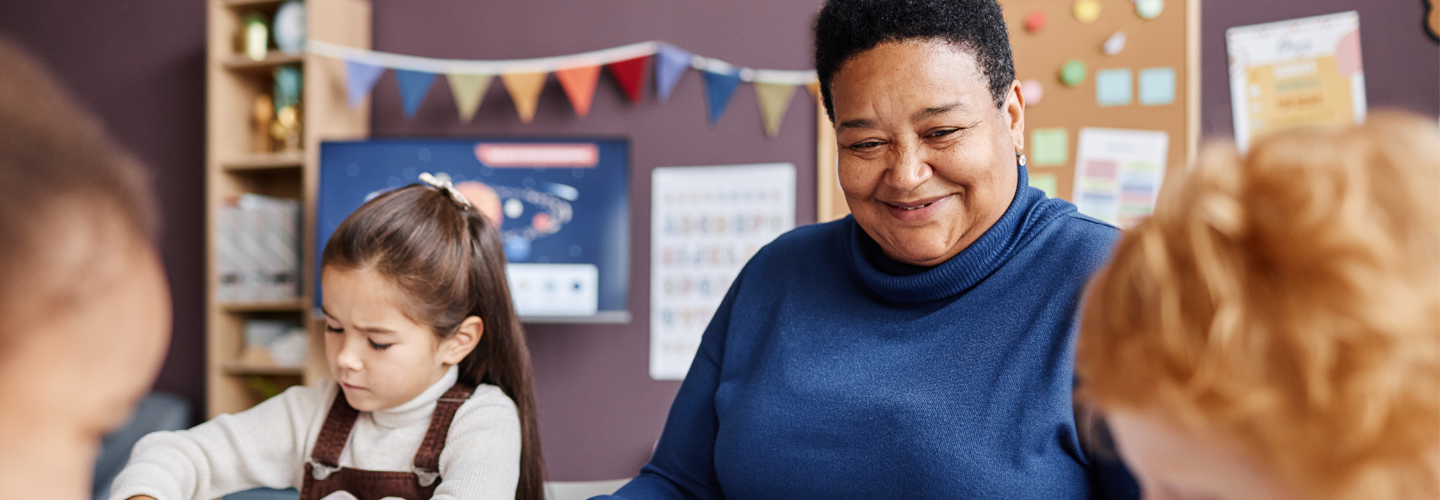 Children engaged in a classroom activity, with colorful educational posters and a banner in the background.