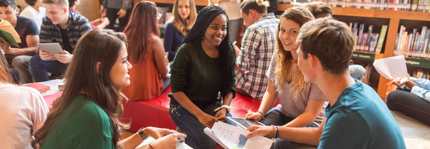 A group of teenagers talking together in a library
