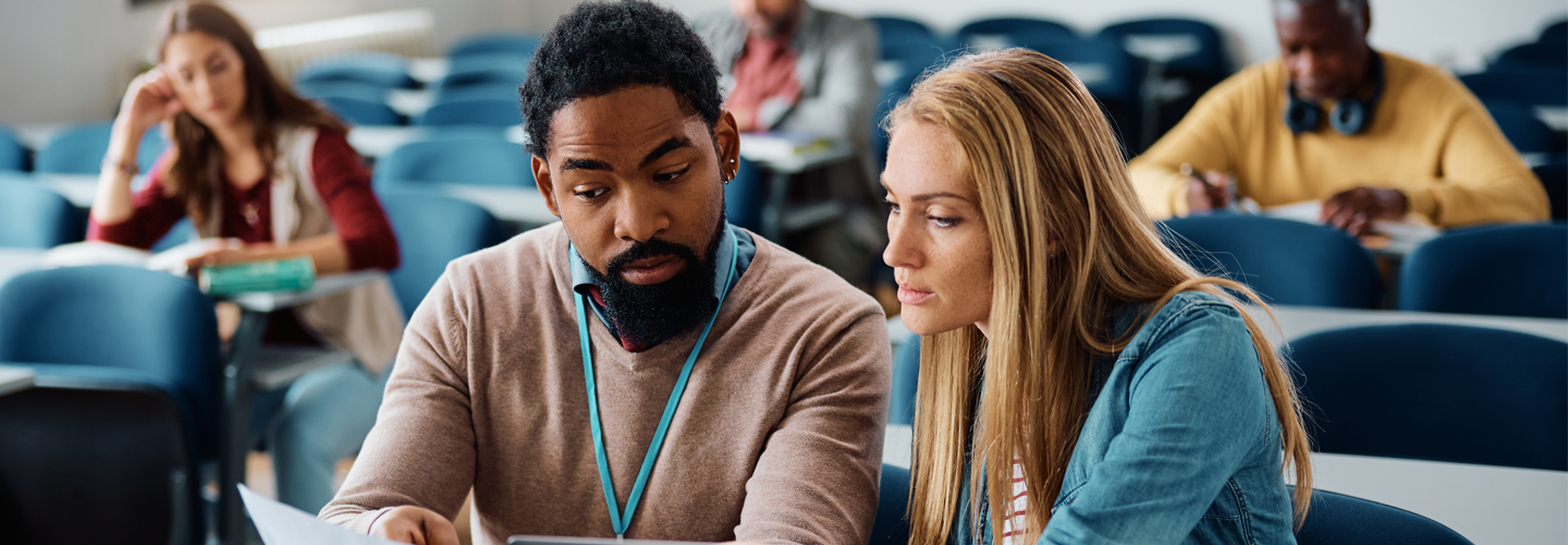 A student and lecturer talking together in a lecture room