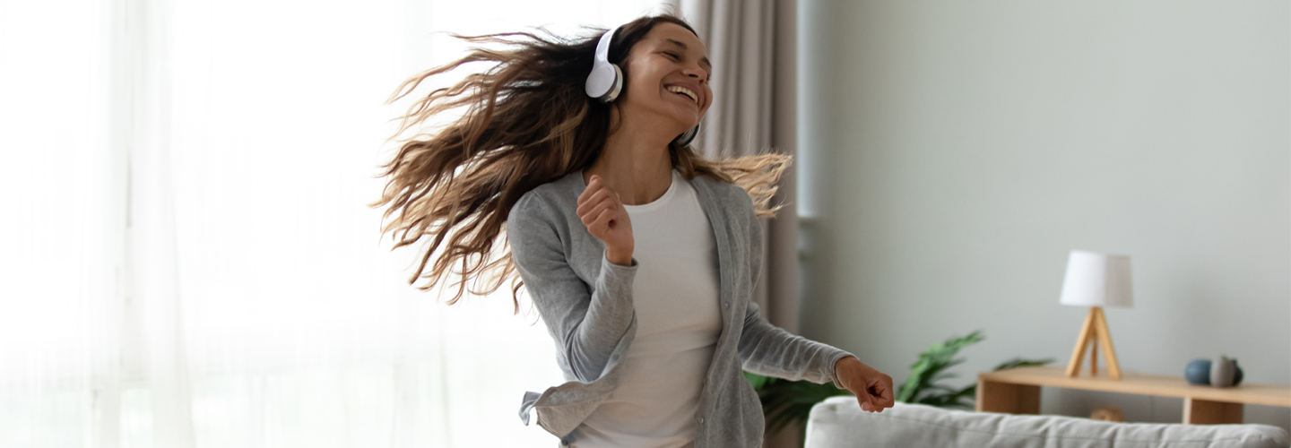 A woman with headphones dancing in her living room