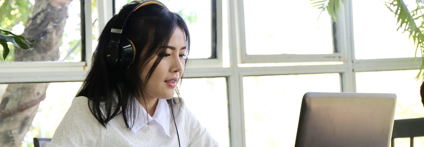 Image of a woman with a headset looking at her laptop