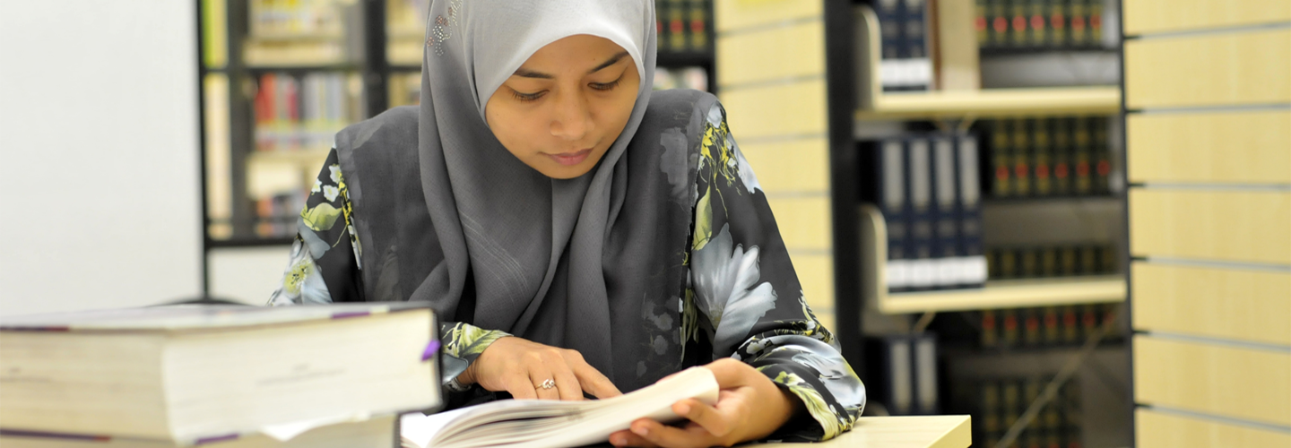 جلست امرأة في مكتبة تقرأ الكتب على طاولة