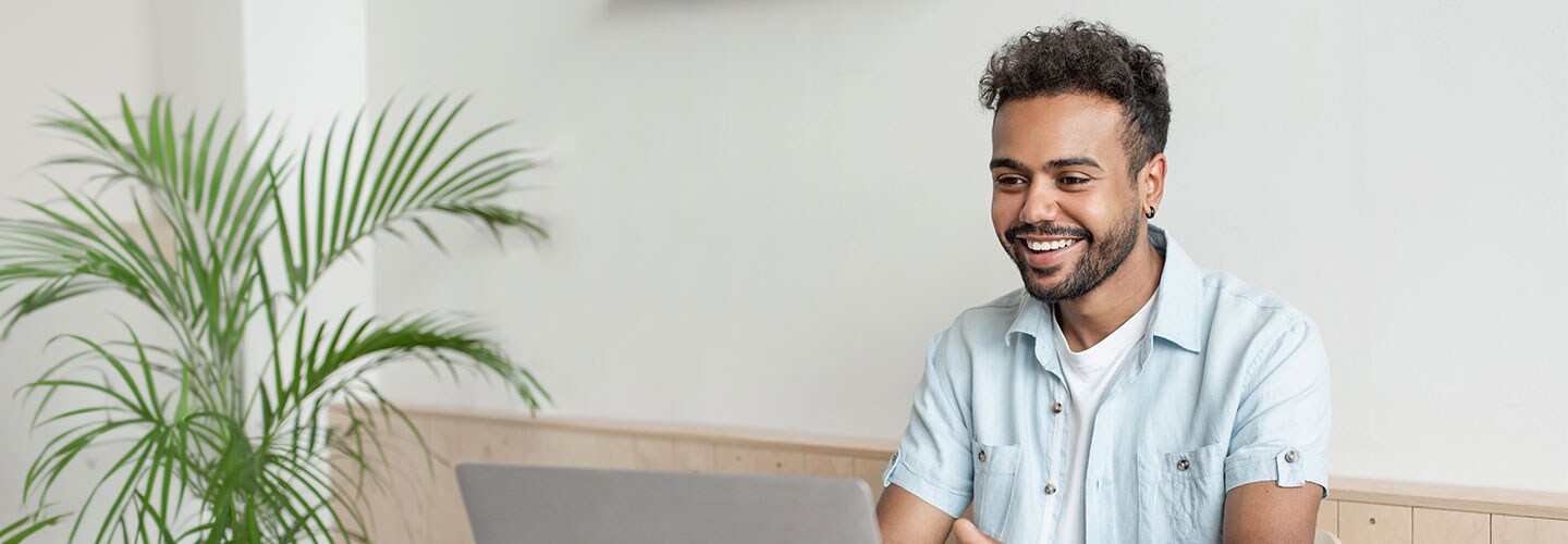 A man sat at a laptop smiling