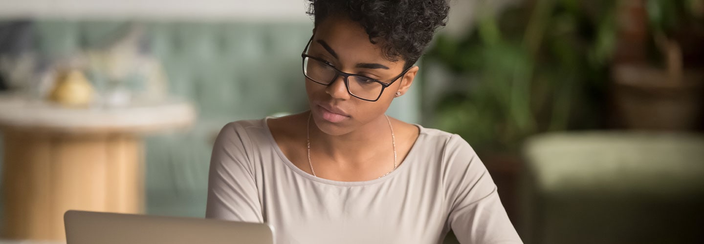 امرأة تدرس على حاسوبها المحمول وتدون ملاحظات في مقهى