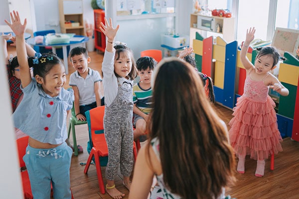 children with their hands up in a classroom activity