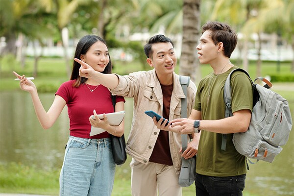 A man and a woman point directions for a man with a rucksack on his back
