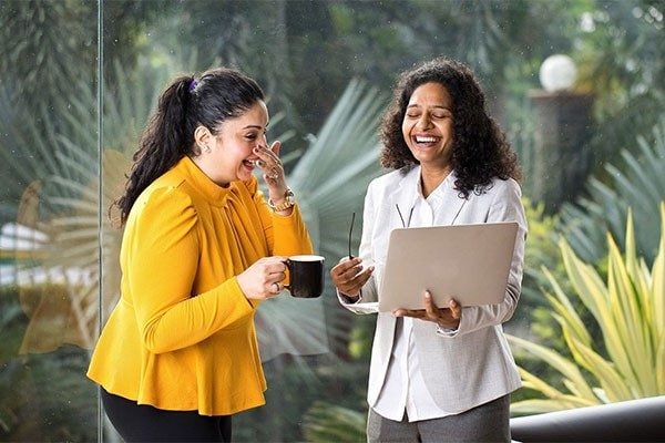 Two female colleagues chatting and smiling in the office