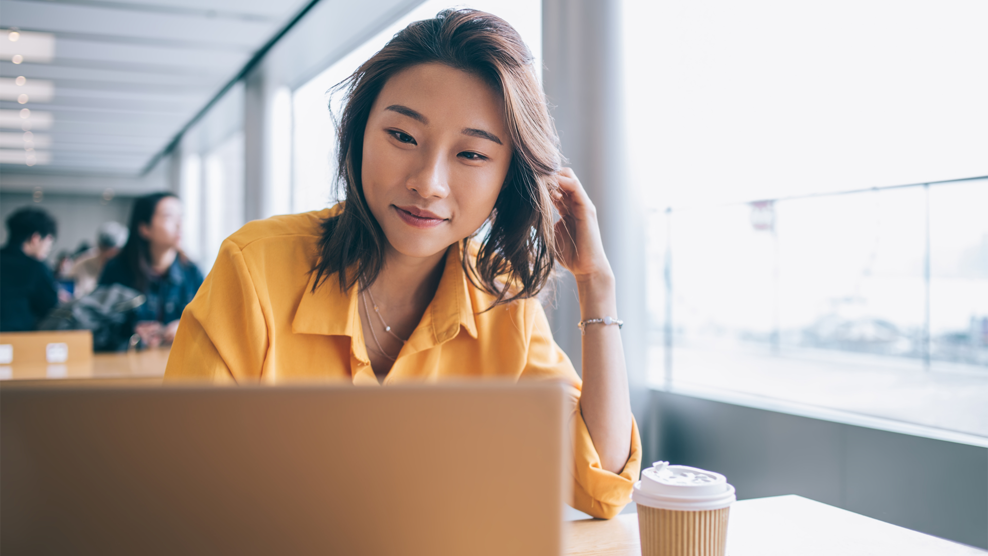 Young woman in a open university space looking at a laptop