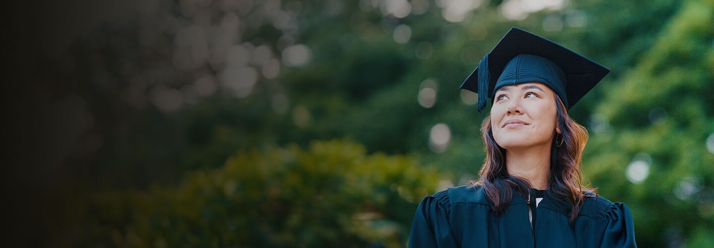 Woman in graduation gown and hat smiling.