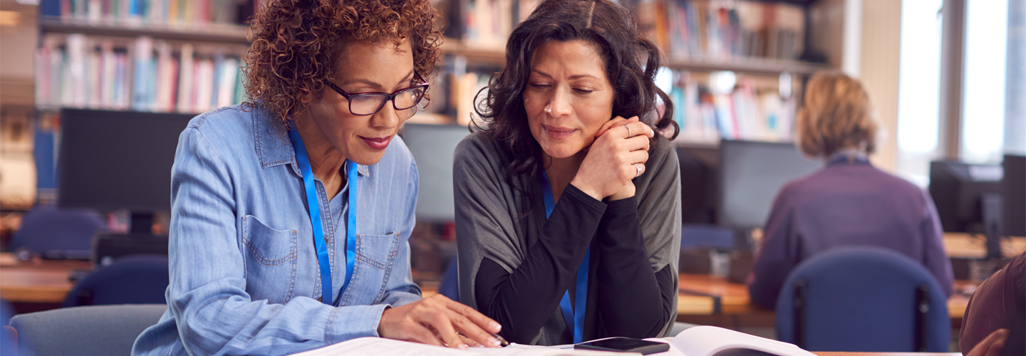 Two teachers sat in a library together talking