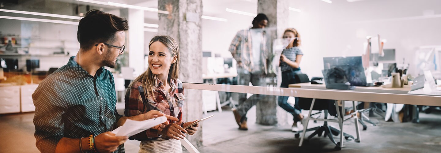 Two colleagues walking and chatting in the office.