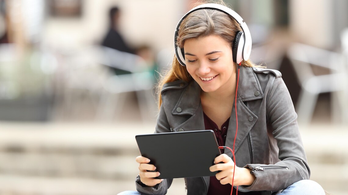 Young person listening to headphones and watching content displayed on a tablet